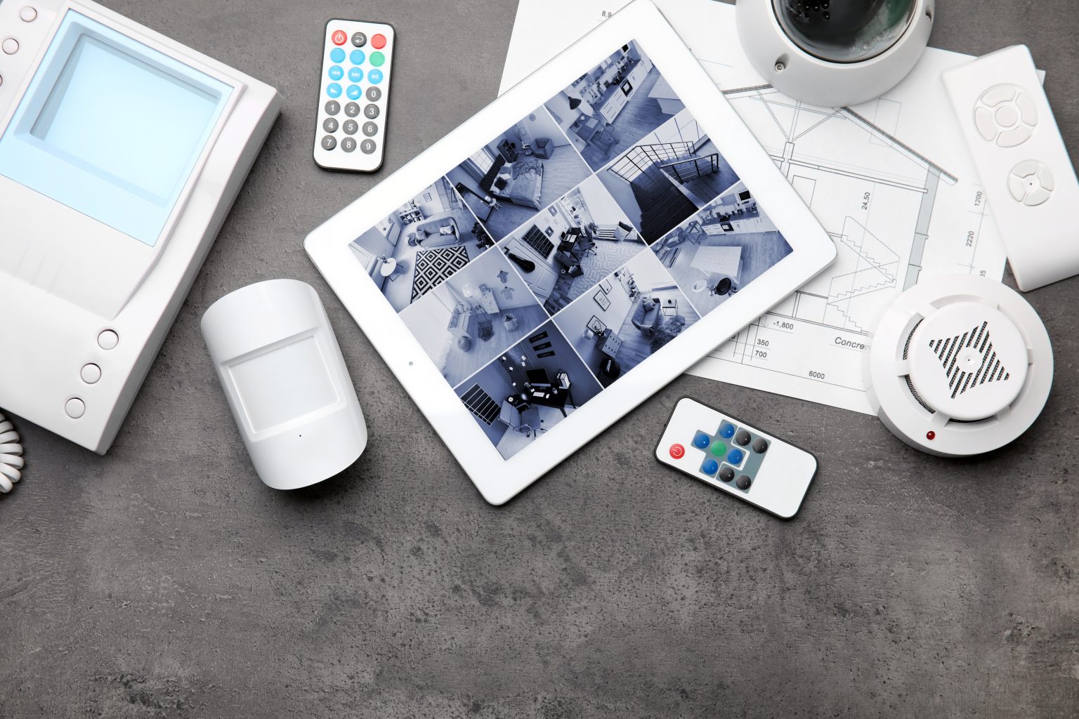 Composition à plat d'une tablette avec images de caméras de vidéosurveillance sur une table grise. Système de sécurité domestique.